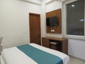 sypialnia z łóżkiem, telewizorem i oknem w obiekcie The Namami Tapovan w mieście Rishikesh