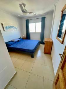 een slaapkamer met een blauw bed en een raam bij Brunella's Apartment - Beach View in San Miguel de Abona