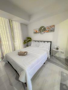 Un dormitorio con una cama blanca con una cesta. en Azure Staycation Suites by MECS, en Manila