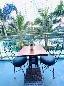 a table and chairs on a balcony with palm trees at Azure Staycation Suites by MECS in Manila
