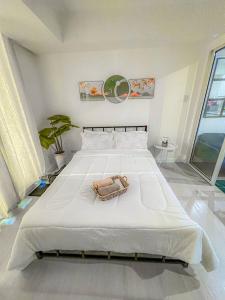 een slaapkamer met een groot wit bed met een handtas erop bij Azure Staycation Suites by MECS in Manilla