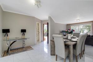 a dining room and living room with a table and chairs at The Cycad. 4-Bed Home next to Clearwater Mall in Roodepoort