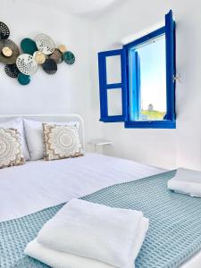 a bedroom with a white bed and a window at mills suites mykonos in Mikonos