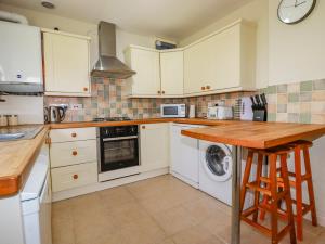a kitchen with white cabinets and a washer and dryer at Little Oaklands in Lostwithiel