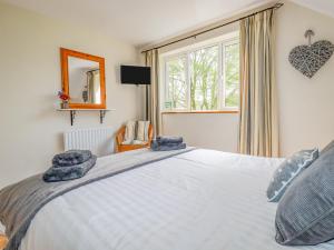 Un dormitorio con una gran cama blanca y una ventana. en Little Oaklands, en Lostwithiel