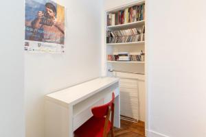 un escritorio blanco con una silla roja junto a un estante de libros en Bright & Stylish 1BD FlatFolies BergèreHaussmann, en París