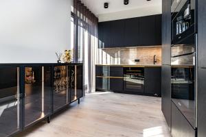 una cucina con armadi neri e pavimenti in legno di Papli Luxury Beach Residence a Pärnu