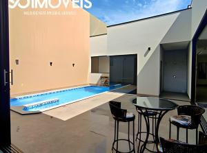 una piscina en una casa con mesa y sillas en Bem-vindo à nossa deslumbrante casa em Caldas Novas!, en Caldas Novas