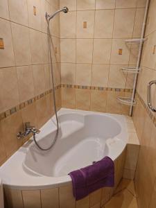 wanna z prysznicem i fioletowy ręcznik w obiekcie Mieszkanie Tarnowo Podgórne w mieście Tarnowo Podgórne