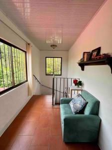 a living room with a green couch and two windows at Finca La Luna - Bed & Breakfast on an organic farm in Concepción