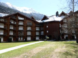 un grande edificio con montagne innevate sullo sfondo di Résidence L'enclave - 3 Pièces pour 6 Personnes 744 a Les Contamines-Montjoie