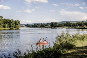 2 personnes dans un bateau sur un lac dans l'établissement Kuscheliges Apartment am Limes, à Rainau