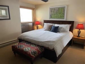 a bedroom with a large bed with two lamps and a ottoman at Spacious 3 Br With Updated Kitchen Condo in Crested Butte