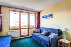 sala de estar con sofá azul y ventana en Appartement bien situé aux Coches - maeva Home 83322, en Les Coches