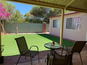 un patio con una mesa y sillas en el césped en double room share bathroom and kitchen en Perth