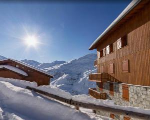 ein schneebedecktes Gebäude mit Sonne im Hintergrund in der Unterkunft Résidence Bosson - 3 Pièces pour 8 Personnes 814 in Les Menuires