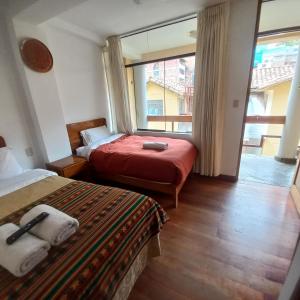 a hotel room with two beds and a large window at Killaqente in Cusco