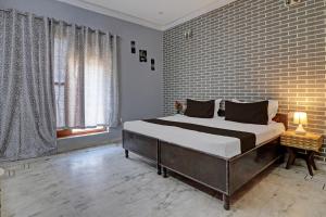 ein Schlafzimmer mit einem großen Bett und einer Ziegelwand in der Unterkunft OYO Hotel Galaxy?s Inn in Gurgaon