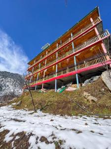 un bâtiment au sommet d'une colline dans la neige dans l'établissement Pahadi Bliss Hostel ,Tosh, à Tosh