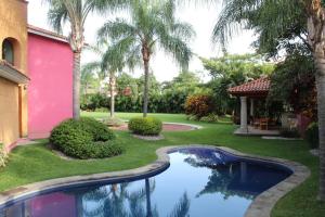 une maison avec une piscine dans une cour avec des palmiers dans l'établissement BILBAO, à Chiconcuac