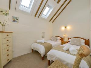 Bigbury的住宿－Bramble Cottage，一间卧室设有两张床、一个梳妆台和窗户。