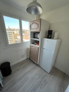 une cuisine avec un réfrigérateur blanc et une fenêtre dans l'établissement Centre ville T2 - Aurillac - Parking Gratuit - Proche de la gare - 1 chambre - 1 canapé lit, à Aurillac