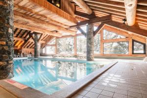 an indoor swimming pool in a building with wooden ceilings at Résidence Les Fermes de Méribel - maeva Home - Appartement pièces Prestige 74 in Les Allues