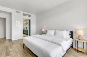 a white bedroom with a large bed and two lamps at Modern & Uncluttered - A Ryson Property in Palm Springs