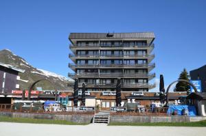 a tall apartment building with a hotel in the background at Résidence Oisans - 2 Pièces pour 5 Personnes 874 in Les Menuires