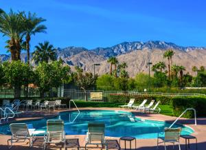 a swimming pool with chairs and mountains in the background at Modern & Uncluttered - A Ryson Property in Palm Springs