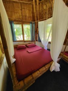 a bedroom with a red bed in a room with windows at Eco-Lodge Deseo Bamboo in Santa Catalina