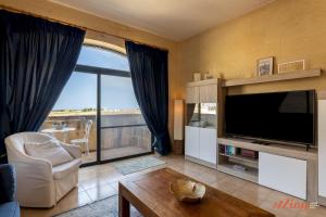 sala de estar con TV y ventana grande en Penthouse with Rooftop Jacuzzi, Stunning Views en Għarb