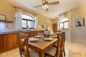 una cucina con tavolo in legno, sedie e ventilatore a soffitto di Penthouse with Rooftop Jacuzzi, Stunning Views a Għarb