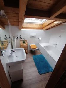 uma casa de banho com uma banheira, um lavatório e um WC. em Ferienwohnung Lechsee em Lechbruck