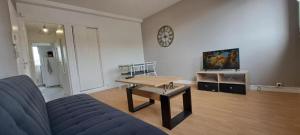 sala de estar con sofá azul y mesa en Centre ville T2 - Aurillac - Parking Gratuit - Proche de la gare - 1 chambre - 1 canapé lit en Aurillac