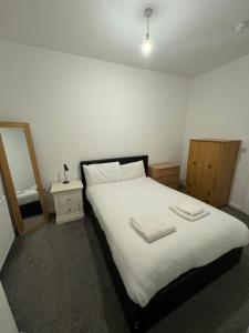 una camera da letto con un letto con lenzuola bianche e uno specchio di Apartology Manchester a Manchester