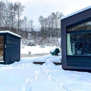un cortile coperto da neve con un edificio e una tenda. di Cabin Westerwald Sauna zubuchbar a Niederdreisbach