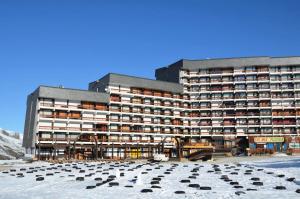 a large building in the snow with a lot of chairs at Résidence Lac Du Lou - Studio pour 4 Personnes 214 in Les Menuires