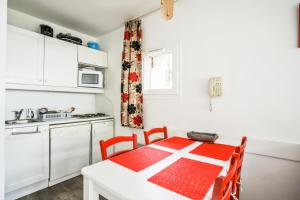 uma cozinha com uma mesa vermelha e branca num quarto em Résidence Le Thabor - maeva Home - Appartement 2 pièces 5 personnes Confort 66 em Le Désert