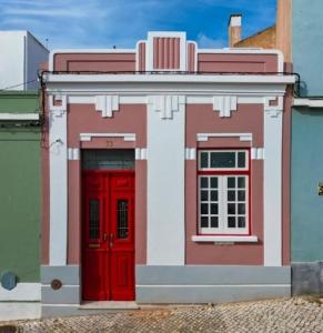 uma casa de lego com uma porta vermelha e janelas em Judice Fialho House em Portimão