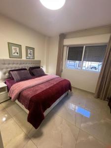 a bedroom with a bed with a red blanket and a window at A Luxury 2 Bedroom With a perfect location in Sweifiyeh in Amman