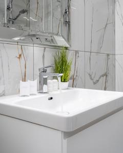 lavabo blanco en el baño con espejo en Warsaw Apartments Bliska Wola, en Varsovia