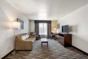 a hotel room with a couch and a desk and a television at Cobblestone Hotel & Suites - Lynden in Lynden