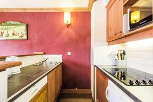 cocina con fregadero y pared roja en Quartier La Forêt - maeva Home - Appartement 3 pièces 6 personnes Sélectio 26 en Valmorel