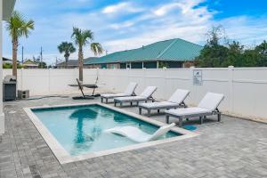 a swimming pool with lounge chairs and a fence at A Slice of Pura Vida in Mexico Beach