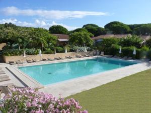 a large swimming pool with chairs and umbrellas at Residence Les Sellettes in Saint-Tropez