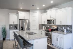 uma cozinha com armários brancos e electrodomésticos de aço inoxidável em Solara Escape em St. George