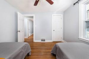 2 camas num quarto com paredes brancas e pisos em madeira em Comfy 4-Bedroom Home - King Bed - Free Parking em Bristol