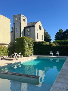 una piscina con 2 sillas y un edificio en Juanita Home (Duplex de dos domitorios en complejo con pileta) en La Plata