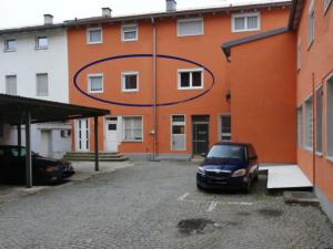 an orange building with a car parked in a parking lot at apanoxa homes I zentral I Bahnhof in Straubing